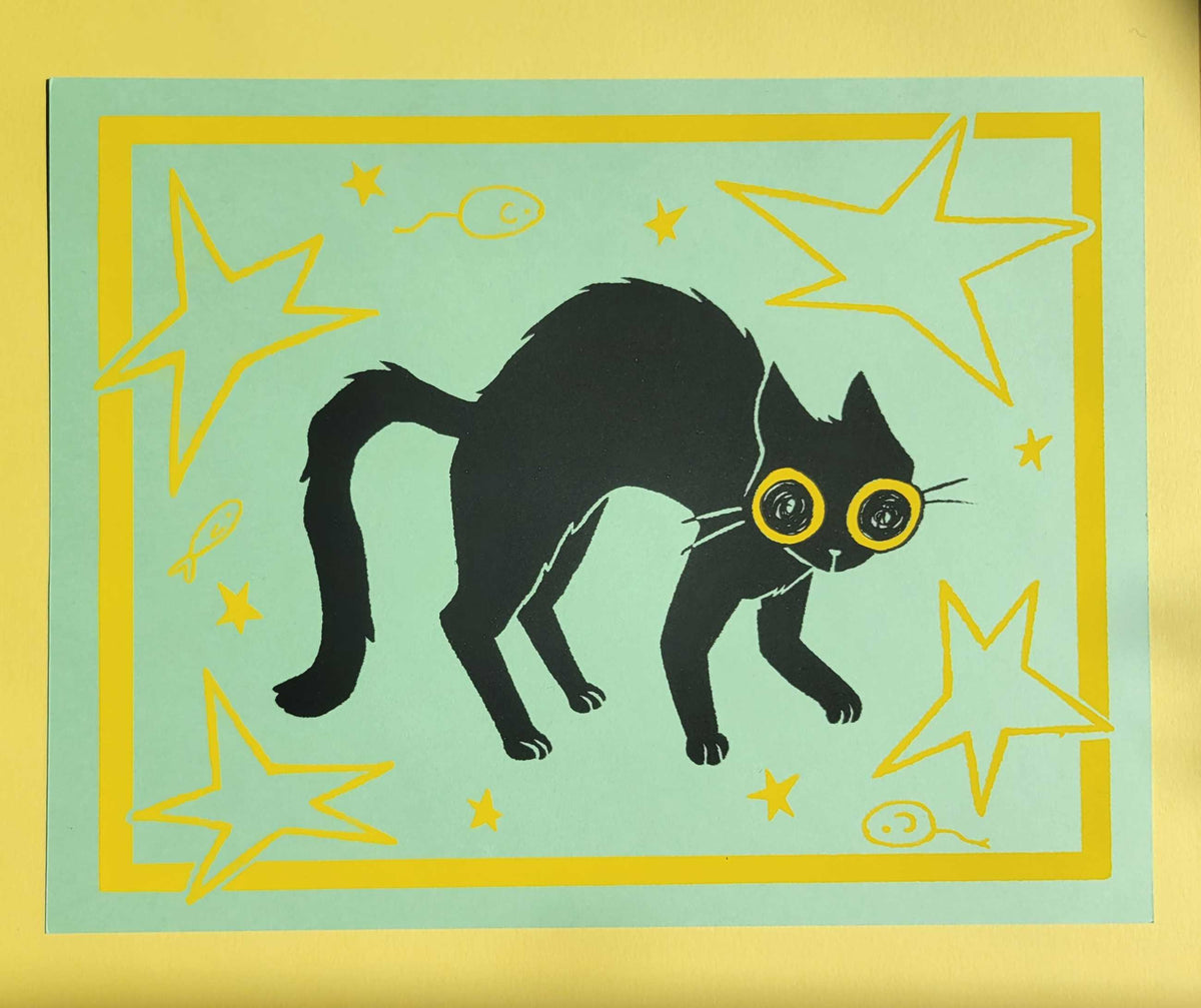 A black cat with yellow eyes on a green background surrounded by stars and toys